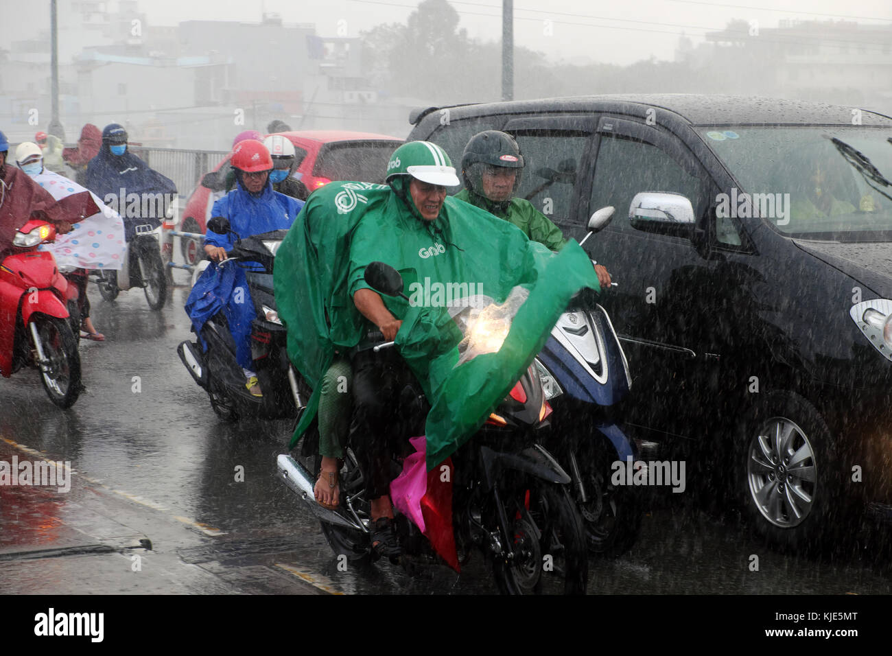 HO CHI MINH CITY, Vietnamese people wear raincoat ride motorcycle, difficult move in heavy rain, high wind from bad weather by tropical low pressure Stock Photo