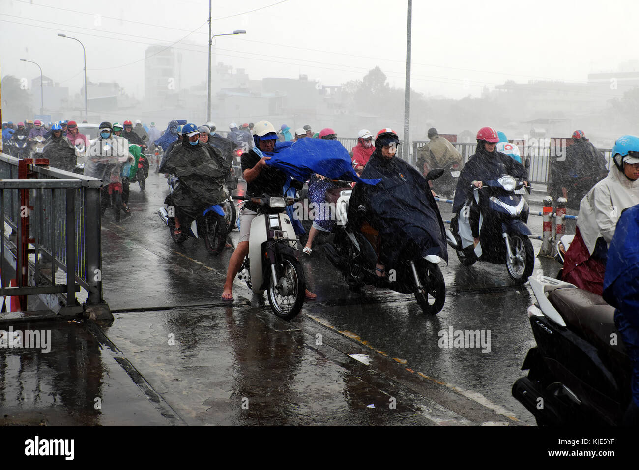 HO CHI MINH CITY, Asian people ride motorbike, difficult move in heavy rain, high wind from bad weather by tropical low pressure after storm, Vietnam Stock Photo