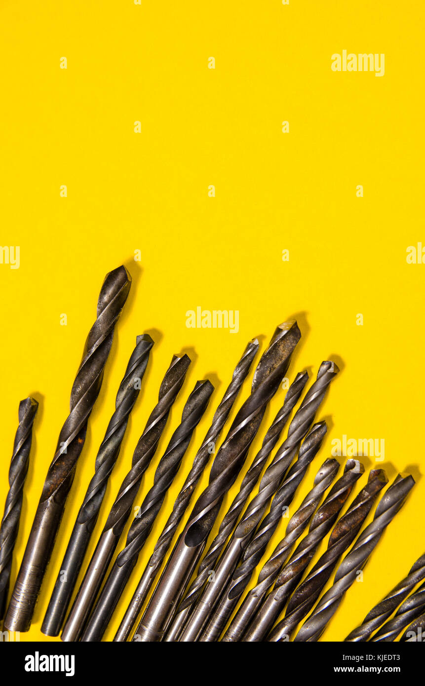 a lot of drills of different sizes on a bright yellow background. vertical view. Stock Photo