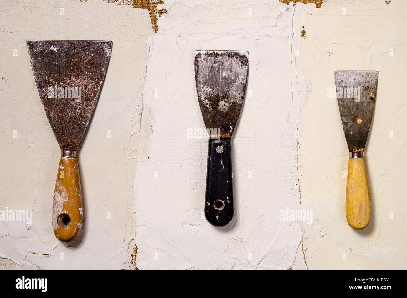three different vintage putty knives on the background of putty Stock