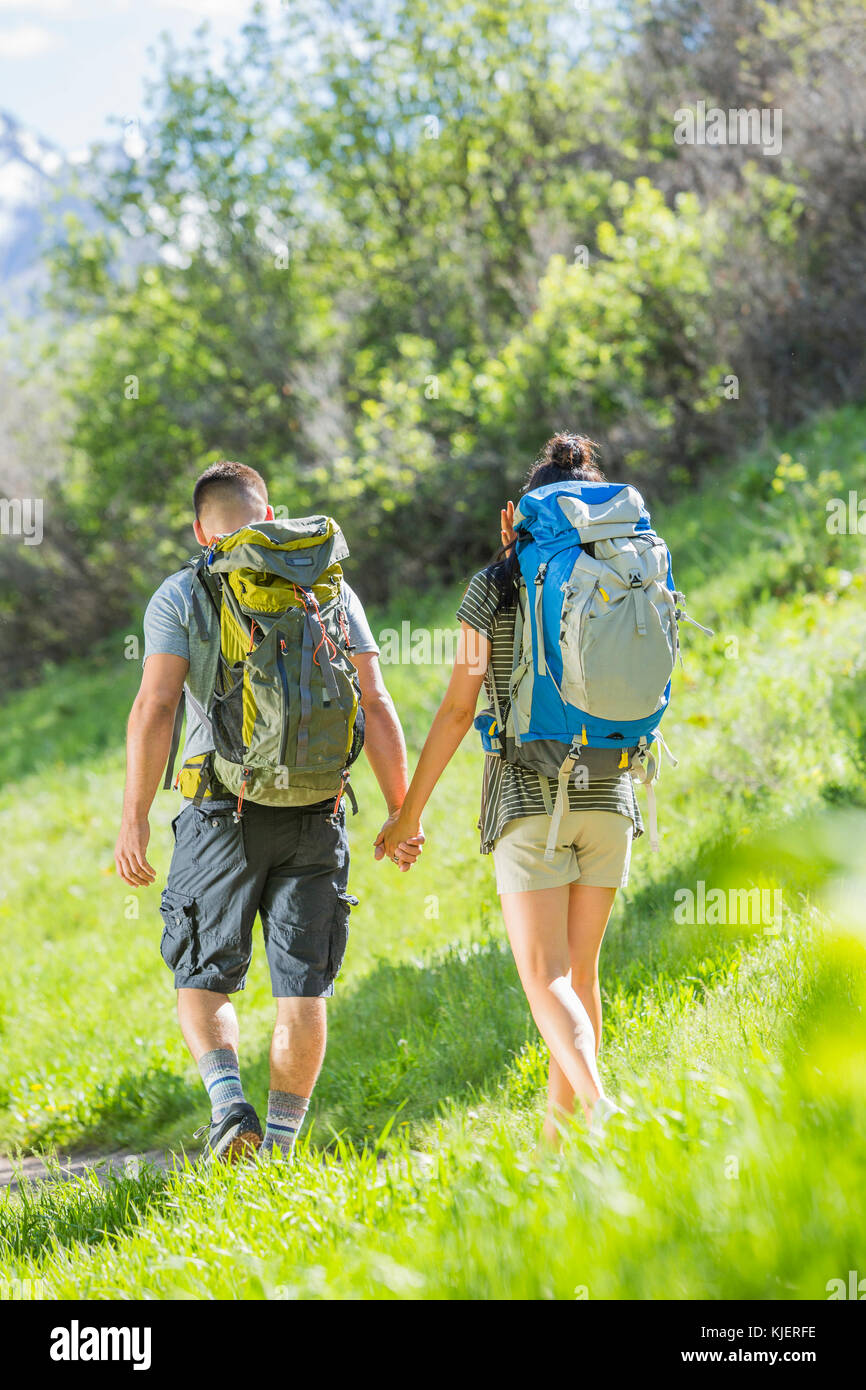 Couple carrying backpacks hiking on hill Stock Photo