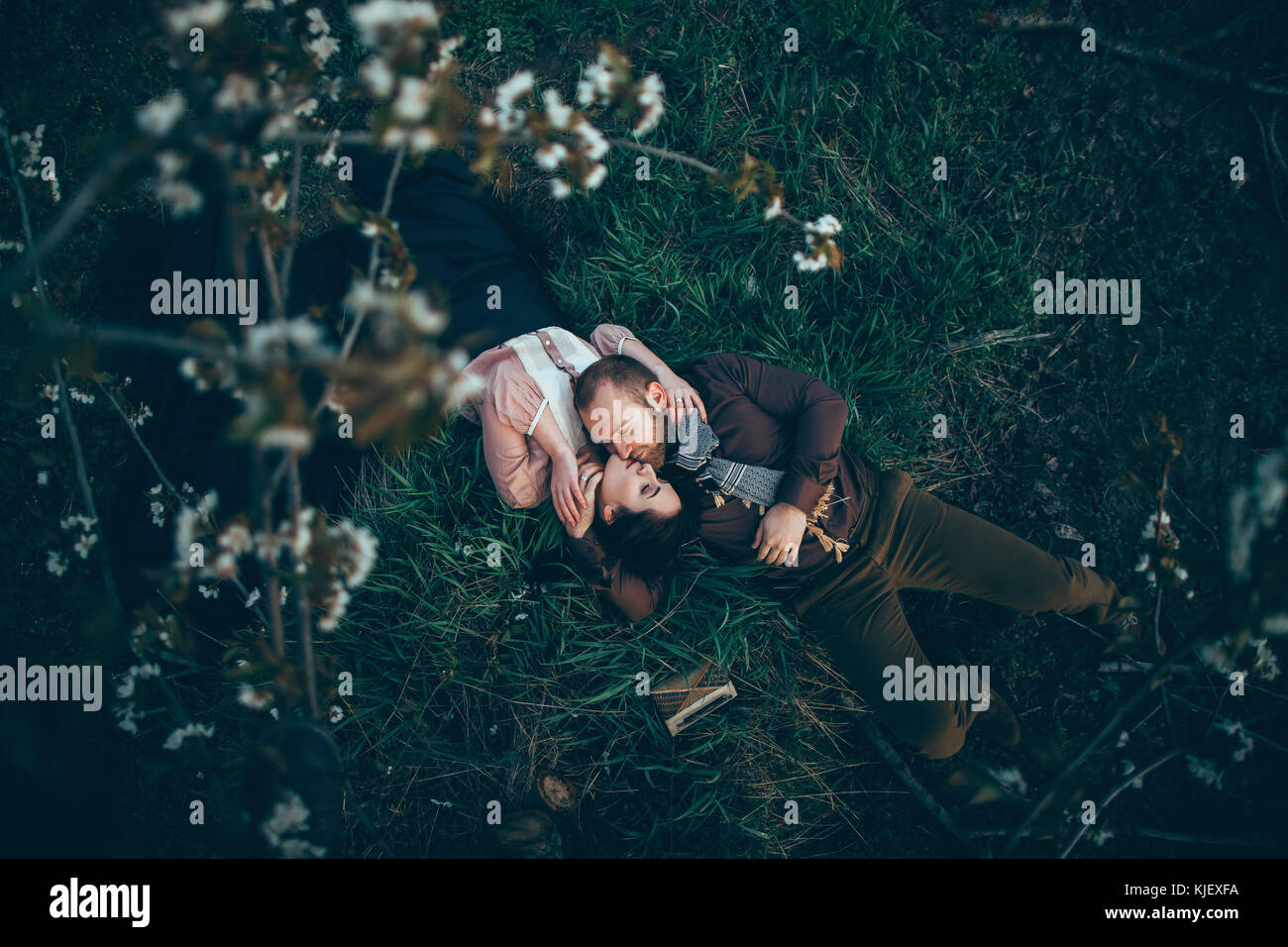 Caucasian couple laying in grass and kissing Stock Photo