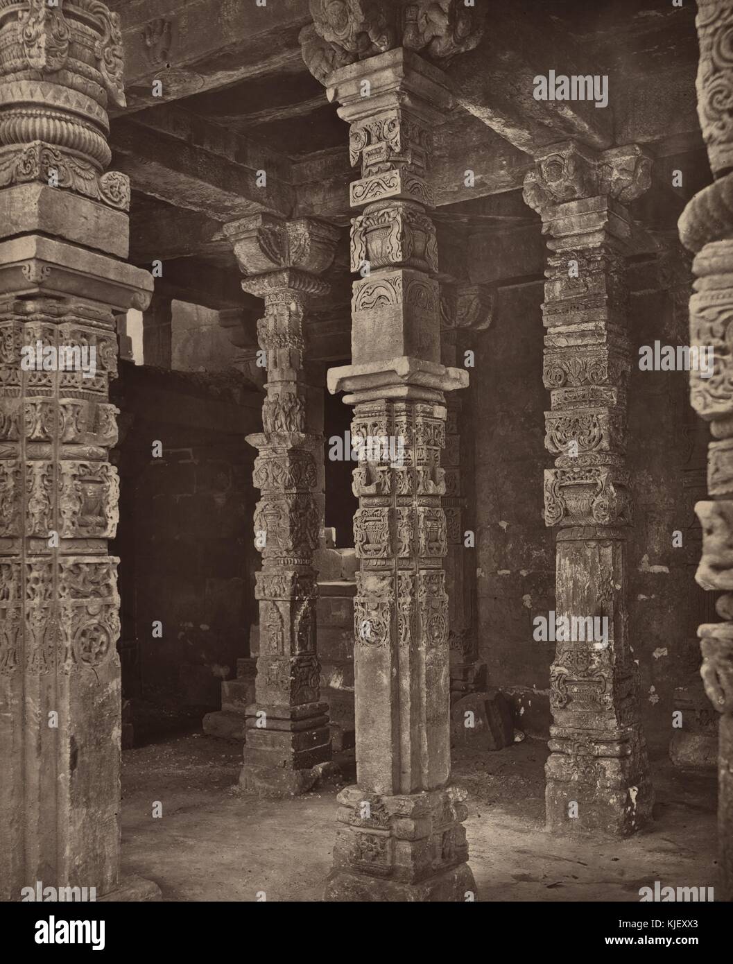 A photograph of a ancient pillars standing in the Qutb Complex, the complex consists of monuments and buildings built by many rules over many hundreds of years, the site is designated as a Uniseco World Heritage Site, Delhi, India, 1872. From the New York Public Library. Stock Photo