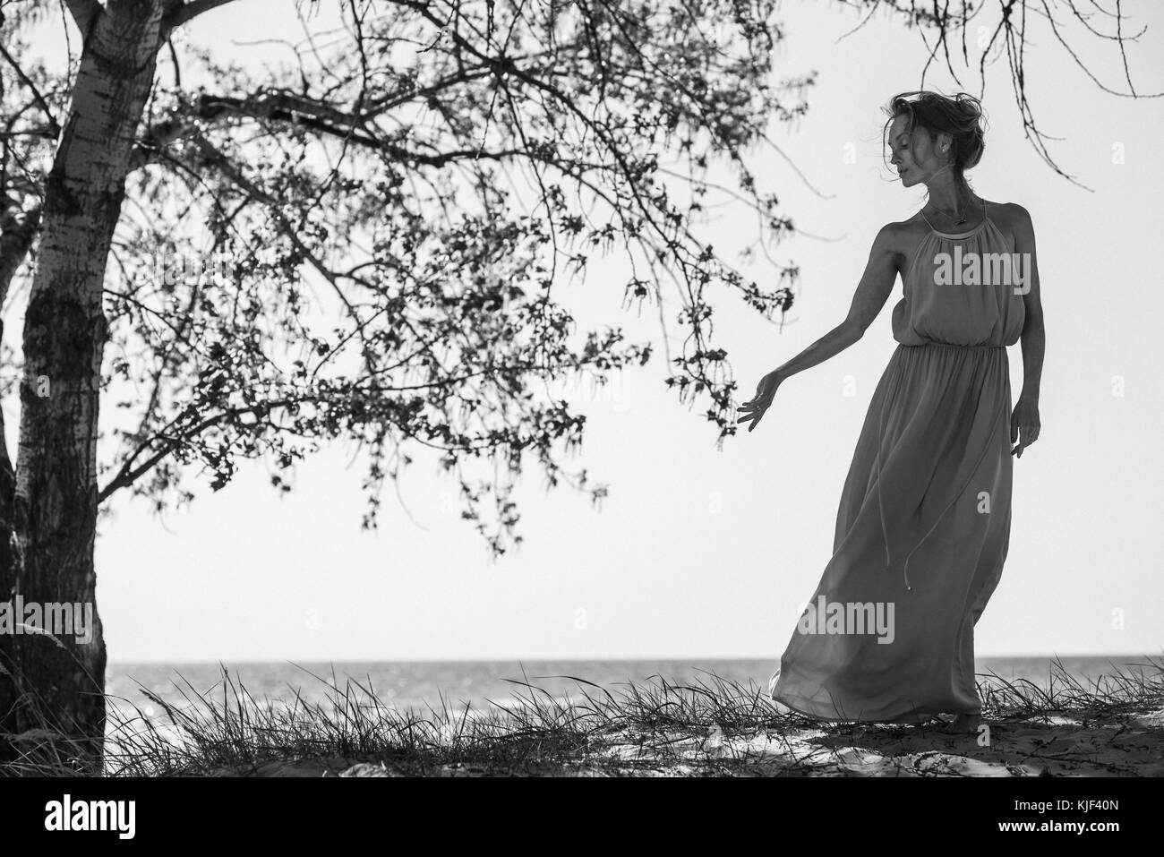 Caucasian woman wearing a dress near tree Stock Photo