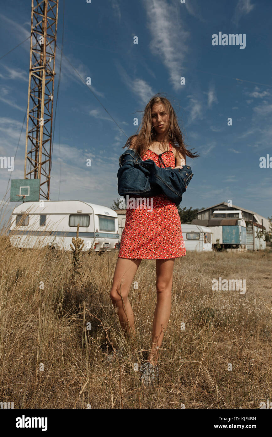 Serious Caucasian woman standing in field near trailers Stock Photo