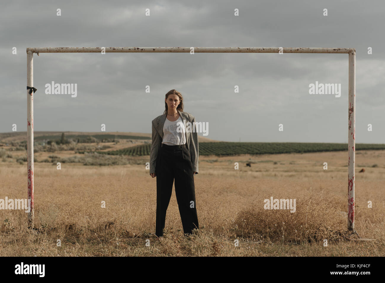 Serious location woman standing in worn soccer goal Stock Photo