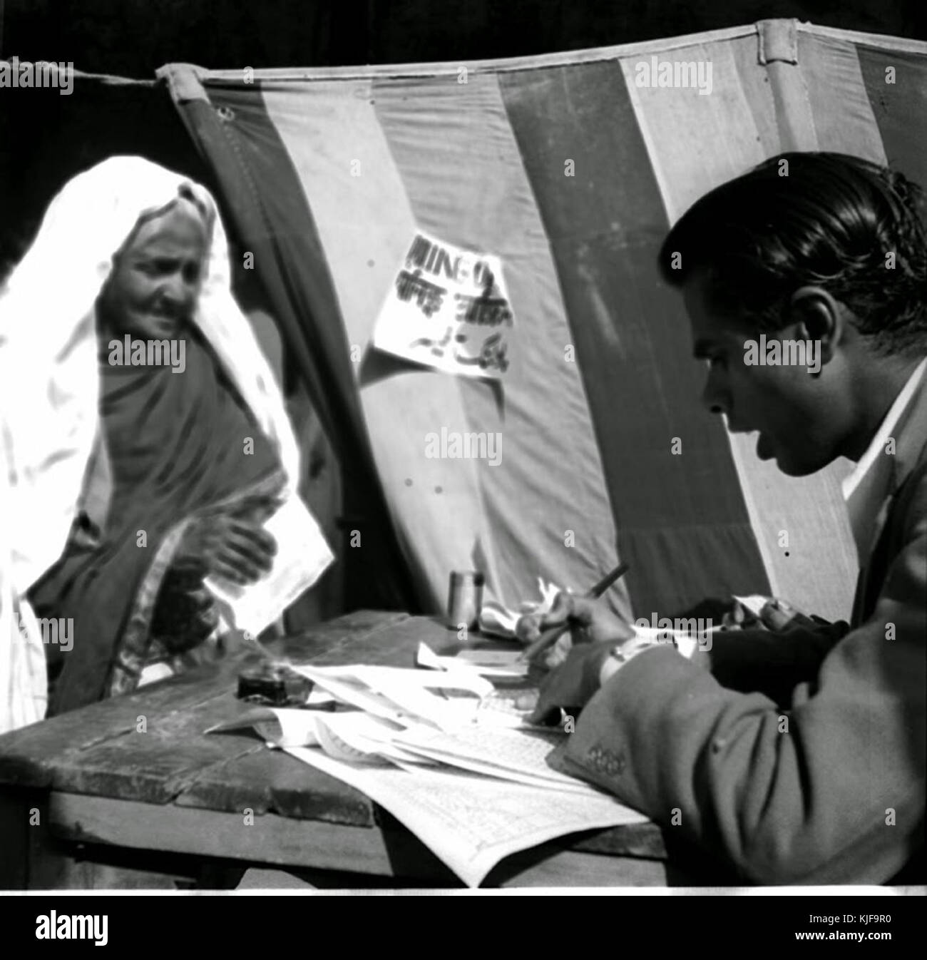An old Muslim woman who came to vote at a polling booth near Jama Masjid, Delhi gets herself identified, before being issued with ballot papers (1952) Stock Photo