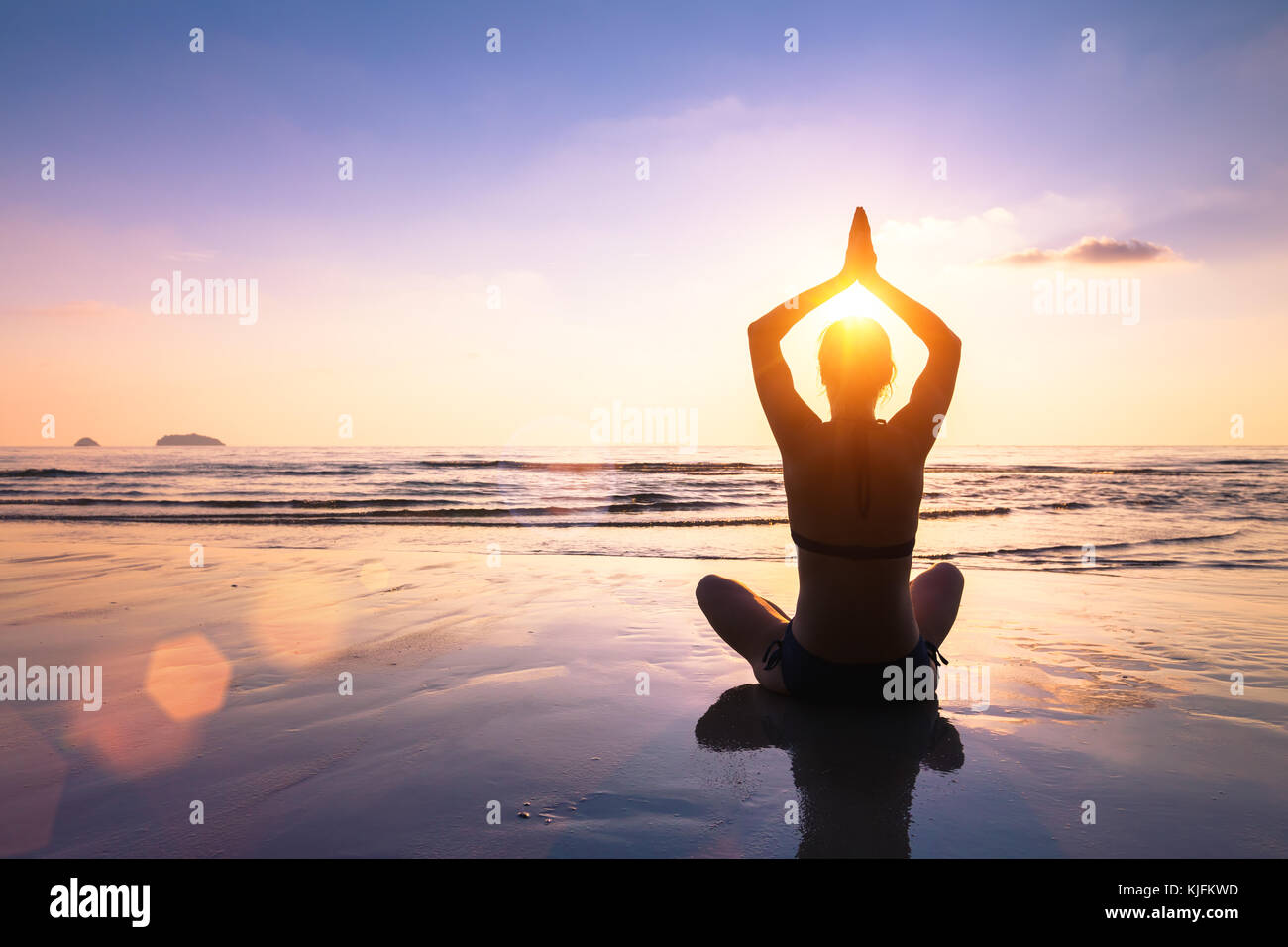 Yoga and meditation on the calm peaceful beach at sunset, fit young woman Stock Photo