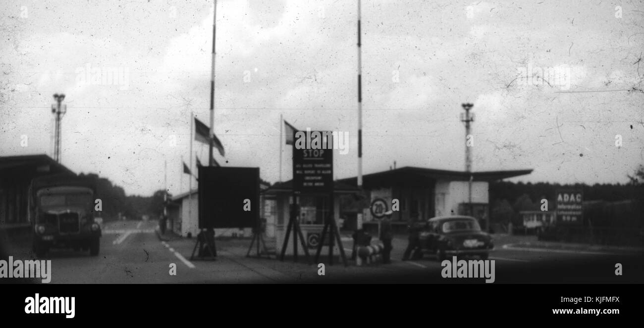 Blurred and damaged photo of military vehicles, cars and inspectors at a checkpoint on the border between East Berlin and West Berlin during the Cold War, with a sign for the Allgemeiner Deutscher Automobil-Club (a German automobile club), taken secretly by an American tourist passing through the checkpoint, Germany, 1965. Stock Photo