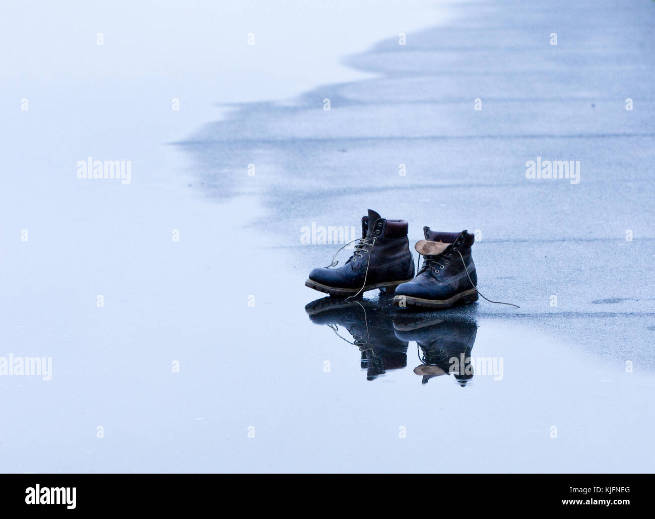 Reflection of hiking boots in a puddle Stock Photo