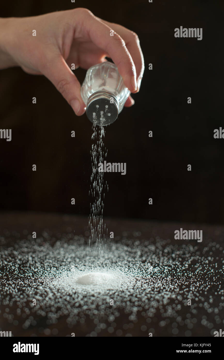 Adding salt. Backlight to salt from salt shaker. Close up Stock Photo
