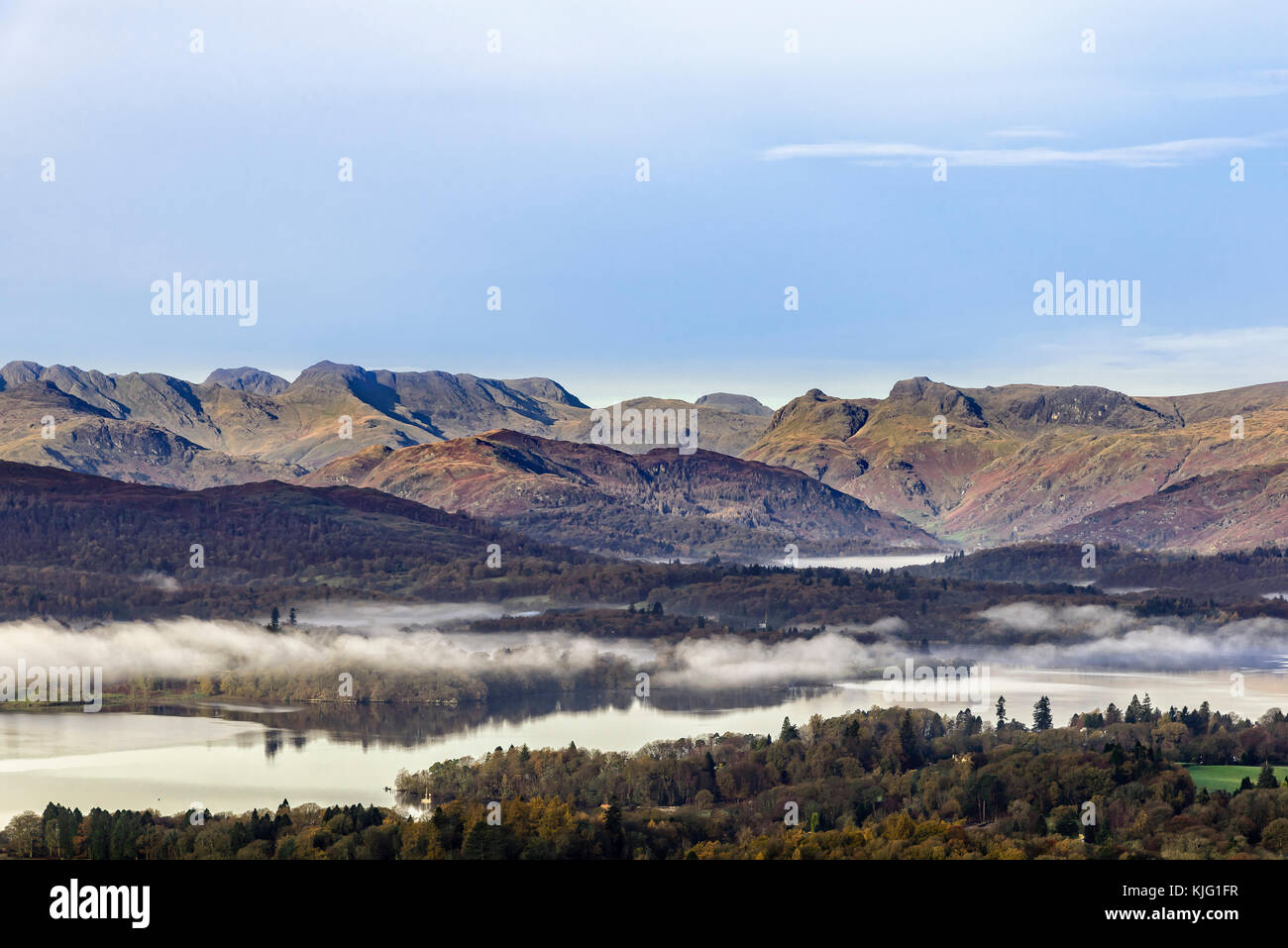 Spectacular view of the high fells from Orrest Head near Windermere with mist hanging over the lake. Stock Photo