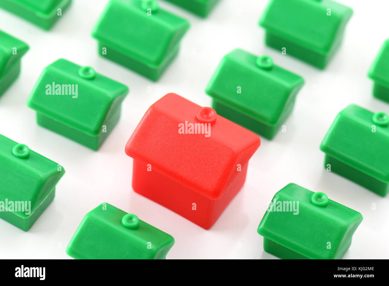 Large red house standing out from small green houses Stock Photo