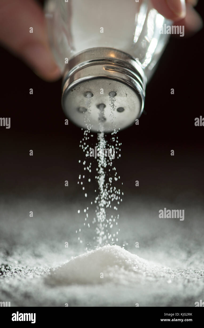 Adding salt. Backlight to salt from salt shaker. Close up Stock Photo