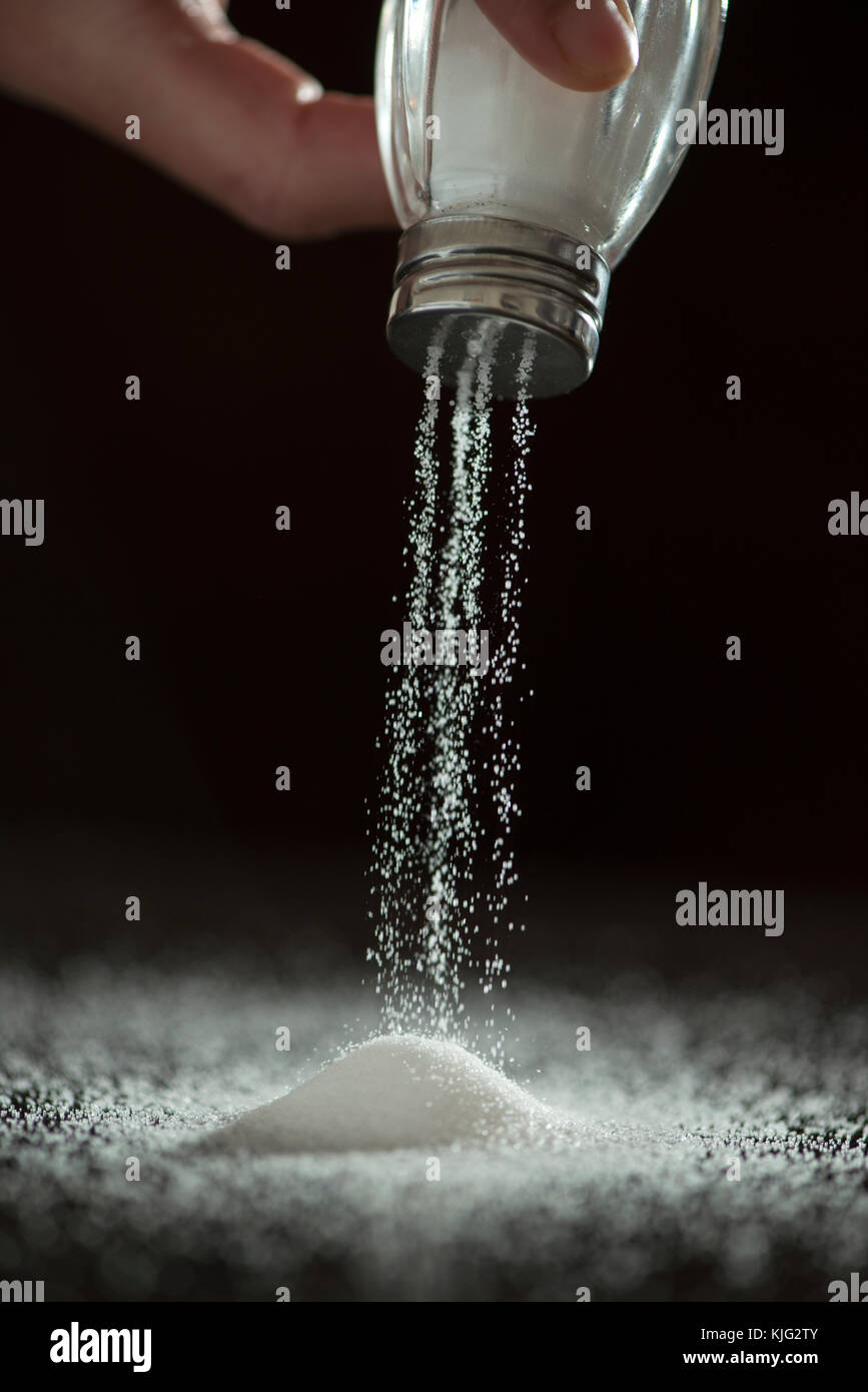 Adding salt. Backlight to salt from salt shaker. Close up Stock Photo