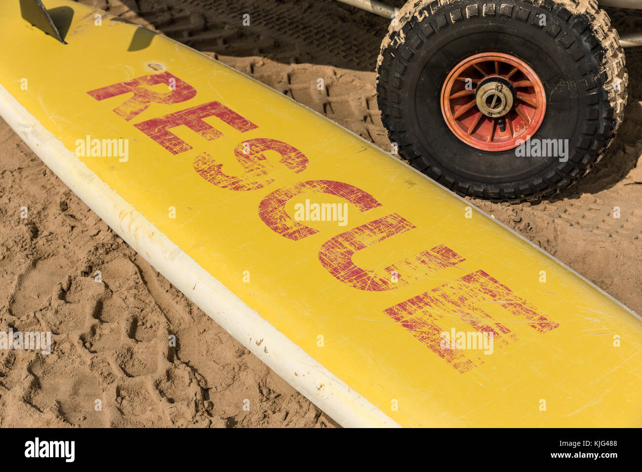 Yellow surfboard on the sand with the word rescue in red Stock Photo
