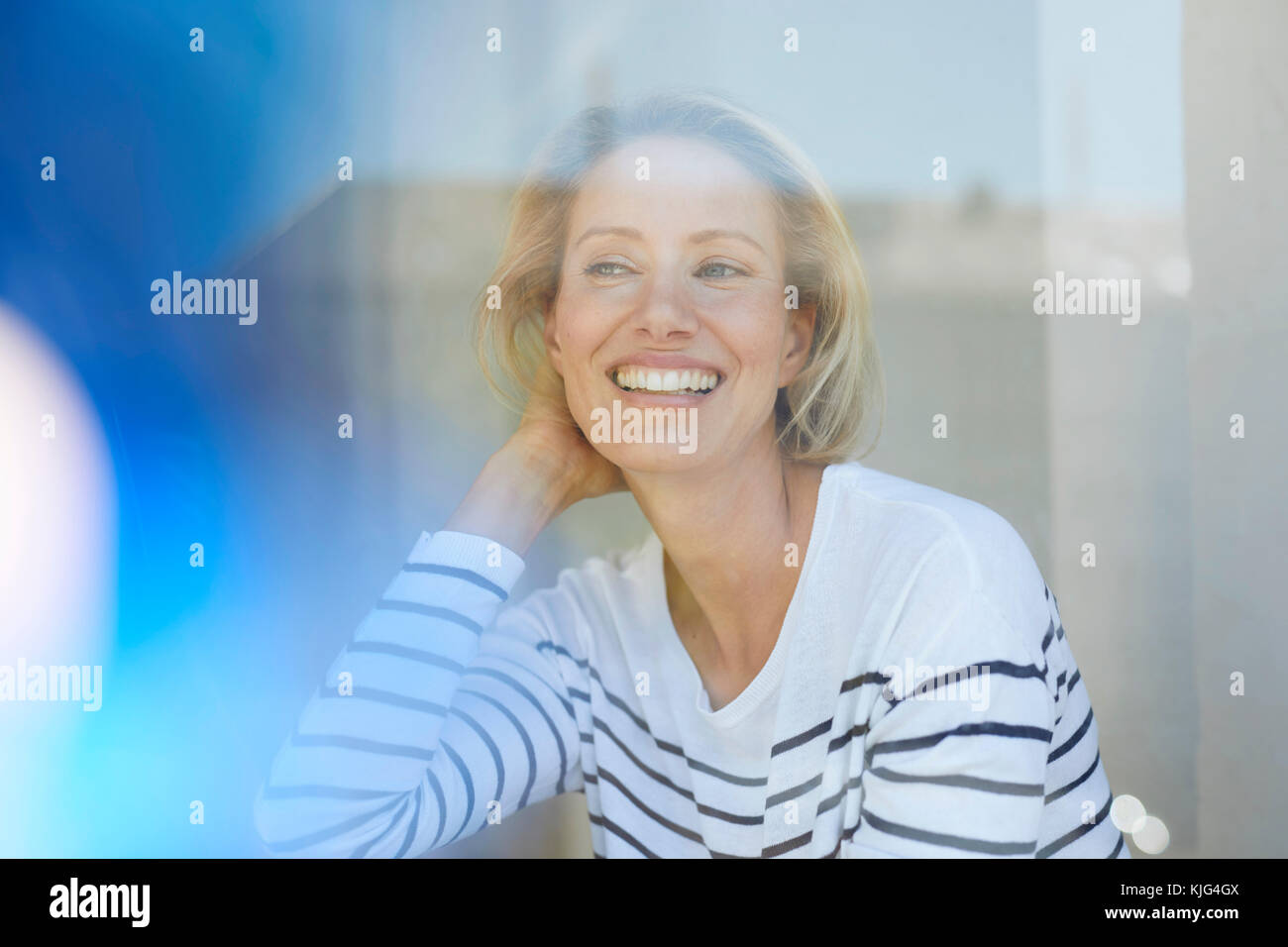 Portrait of laughing blond woman behind window pane Stock Photo Alamy