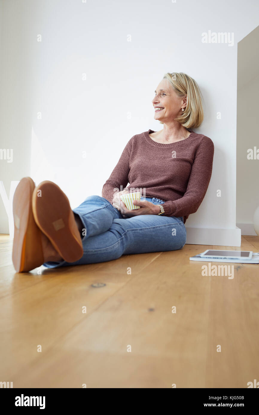Smiling mature woman at home sitting on the floor Stock Photo - Alamy