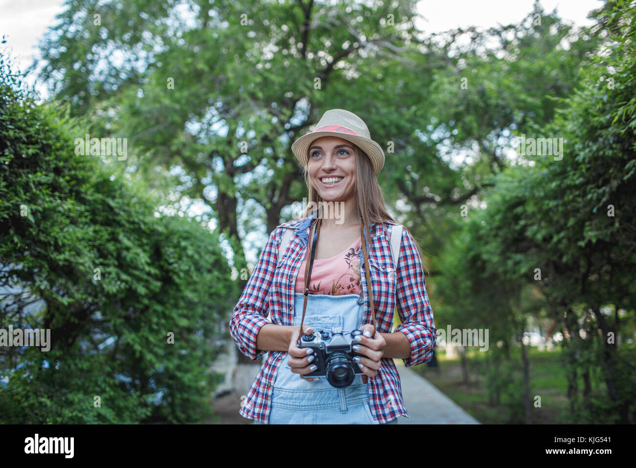 Smiling young woman with a camera in a park Stock Photo - Alamy