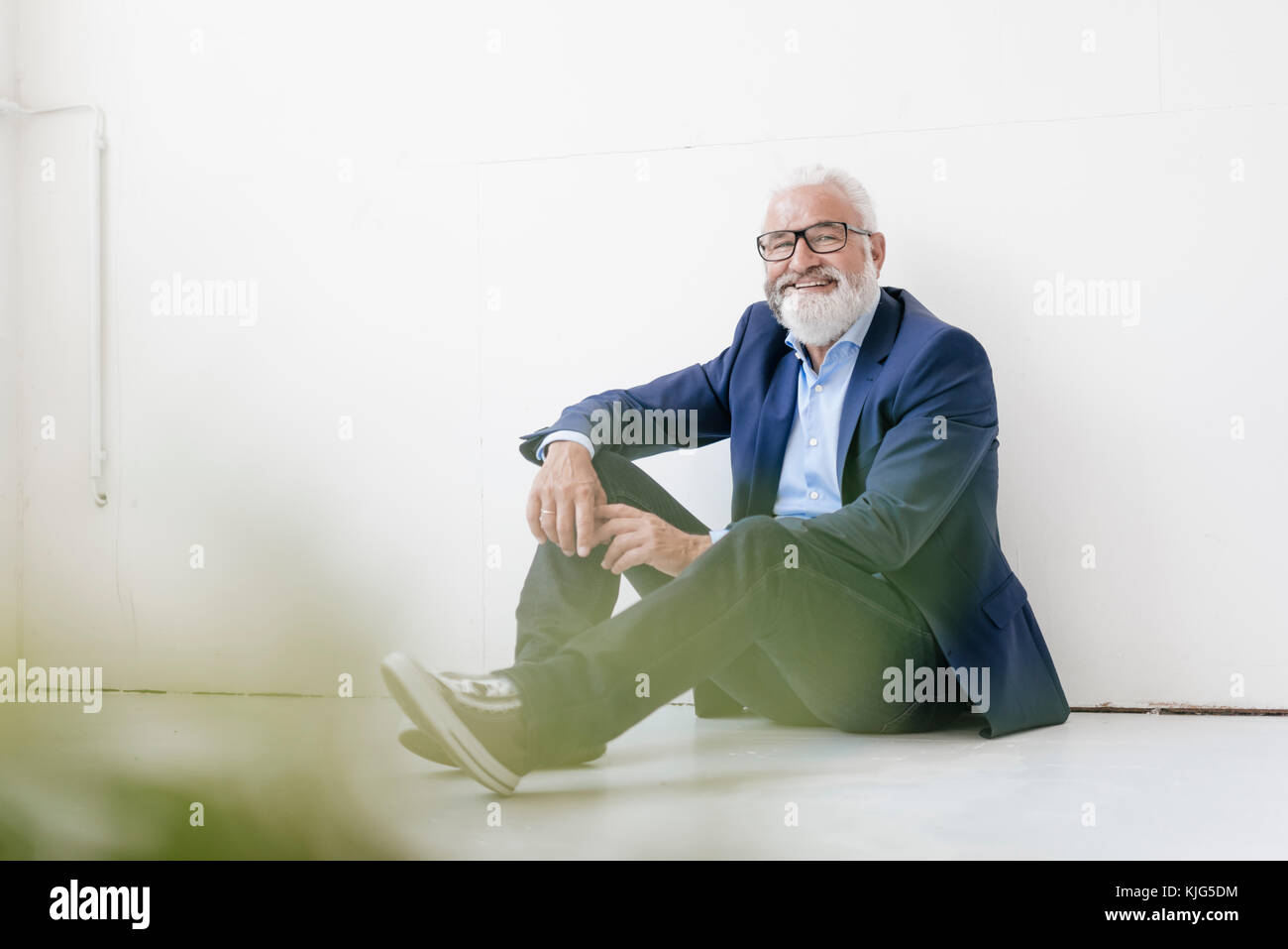 Smiling mature man sitting on the floor Stock Photo - Alamy