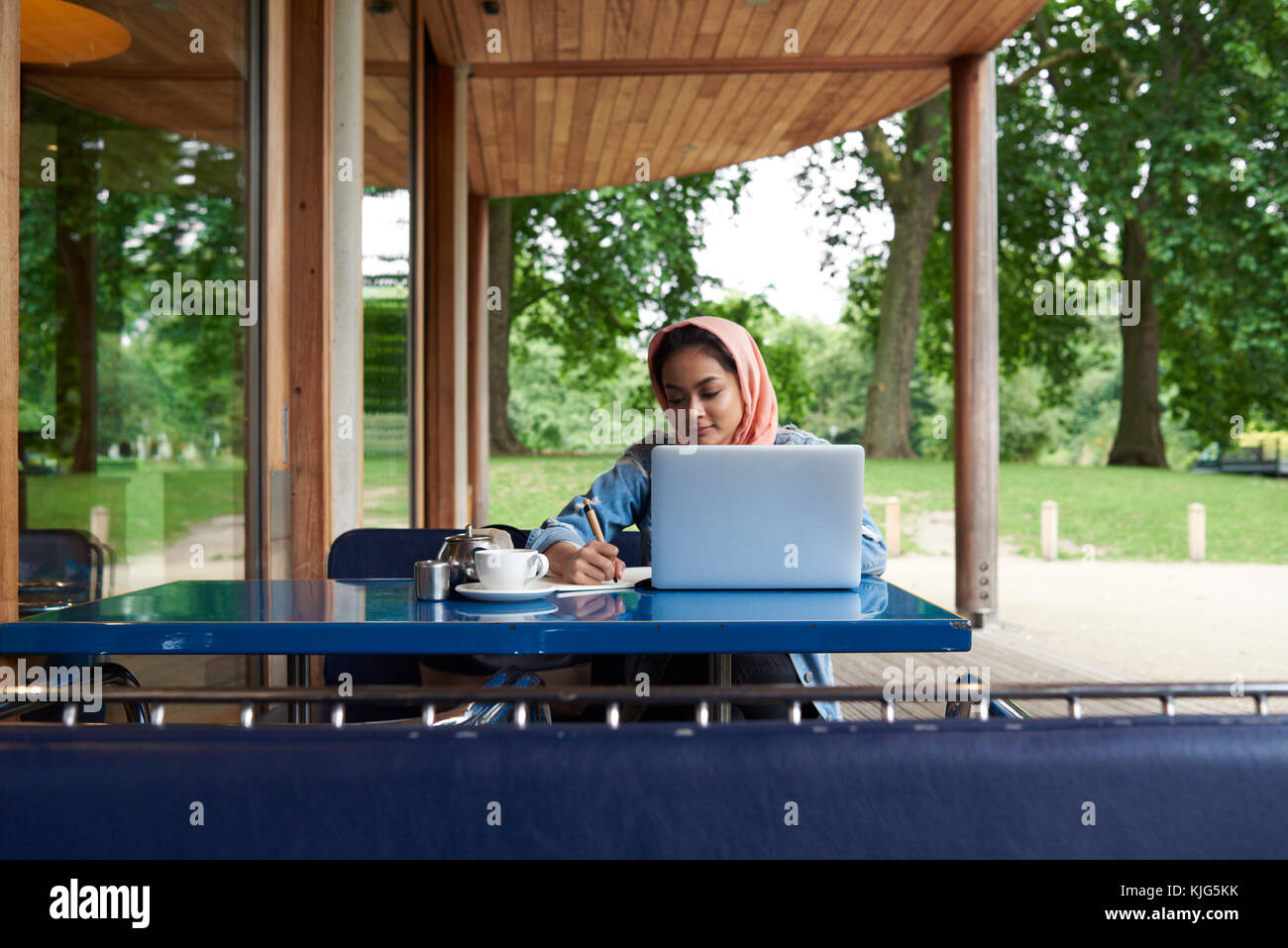 Young woman wearing hijab studying with her laptop on a terrace of a ...
