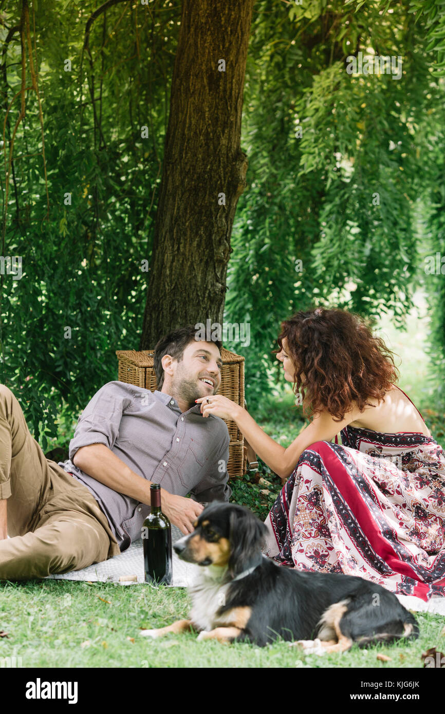 Couple with dog having a picnic in a park Stock Photo - Alamy