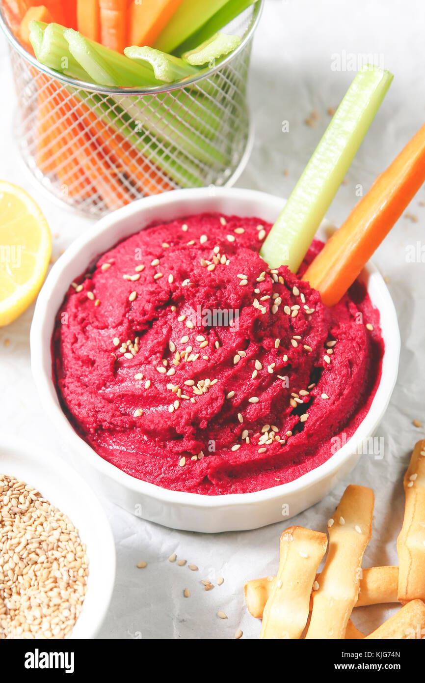 Bowl of beetroot hummus, sesame, carrot and celery crudites and