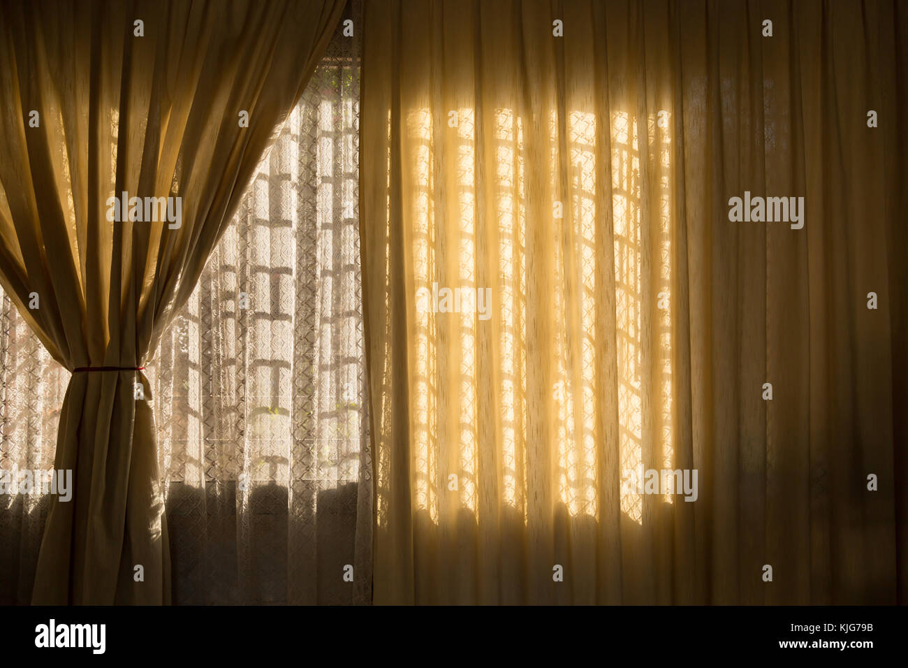 Sunlight from outside window streams into a room through thin lace