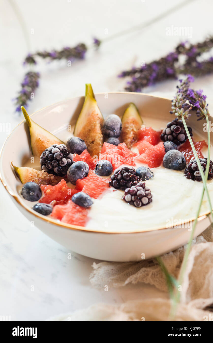 Bowl of Greek yoghurt with fig, watermelon, frozen berries and lavender