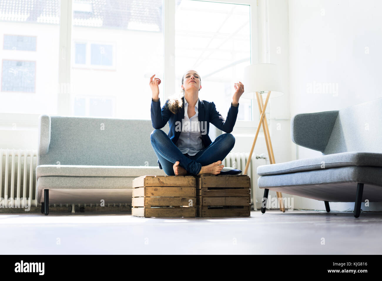 Businesswoman sitting on crate practising yoga Stock Photo