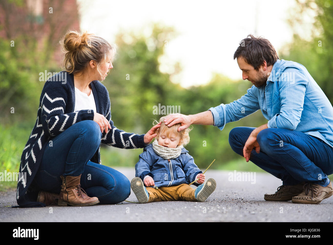 Parents stroking cute little boy on field path Stock Photo - Alamy
