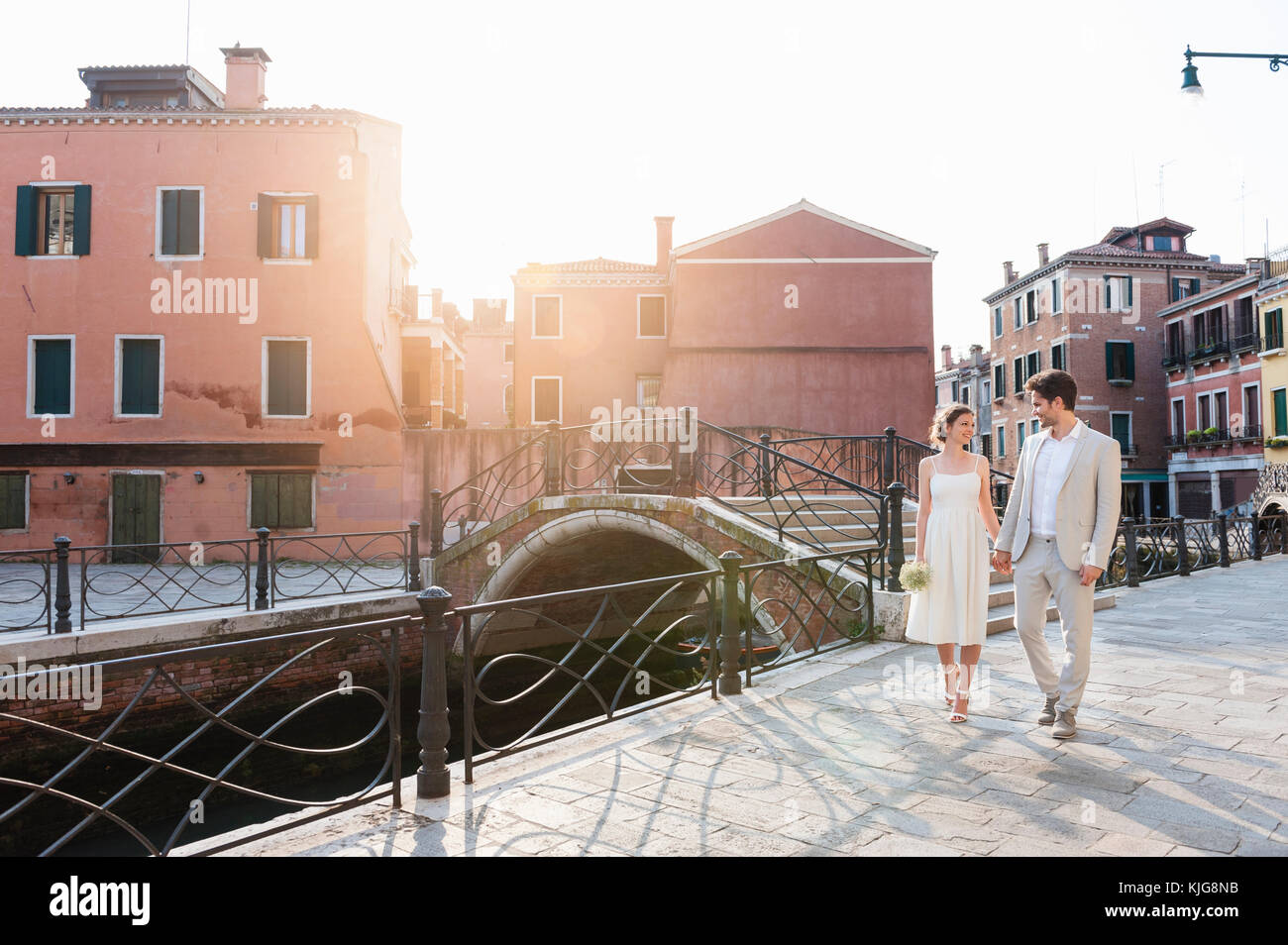 Italy, Venice, bridal couple walking hand in hand at sunrise Stock Photo