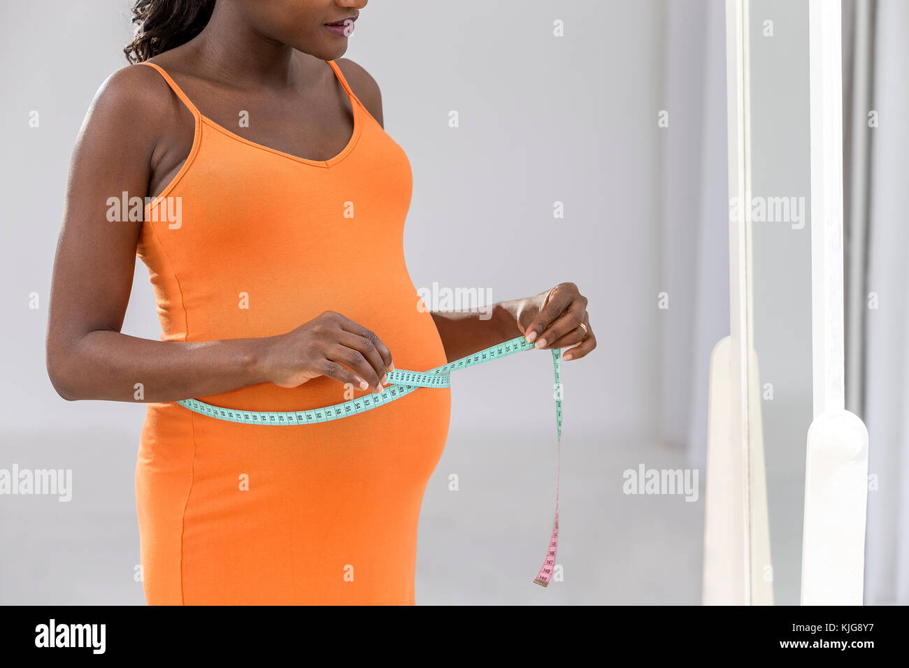 Pregnant woman measuring her belly with the tape profile view Stock Photo