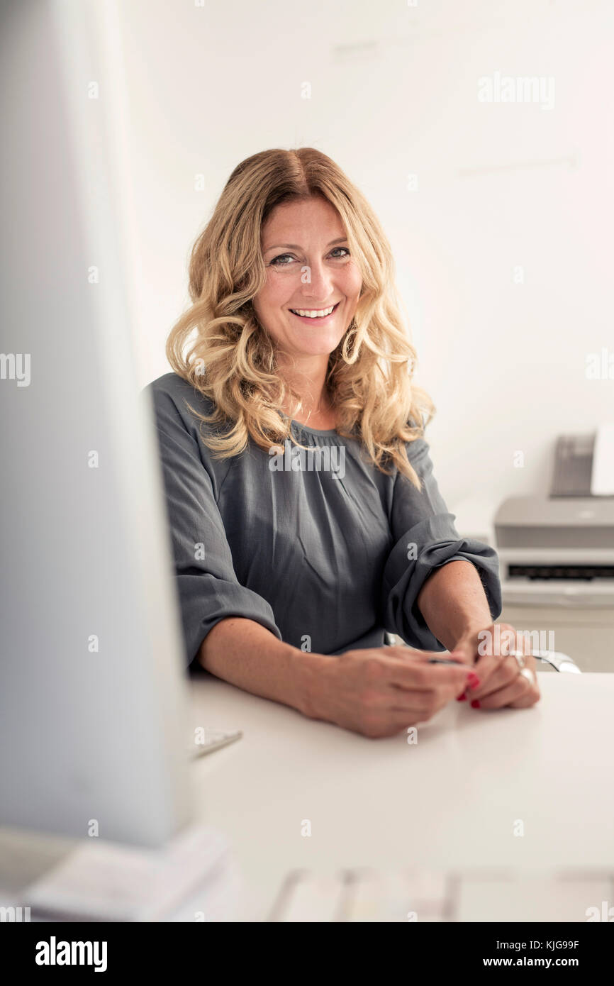 Portrait of smiling businesswoman at desk in office Stock Photo - Alamy