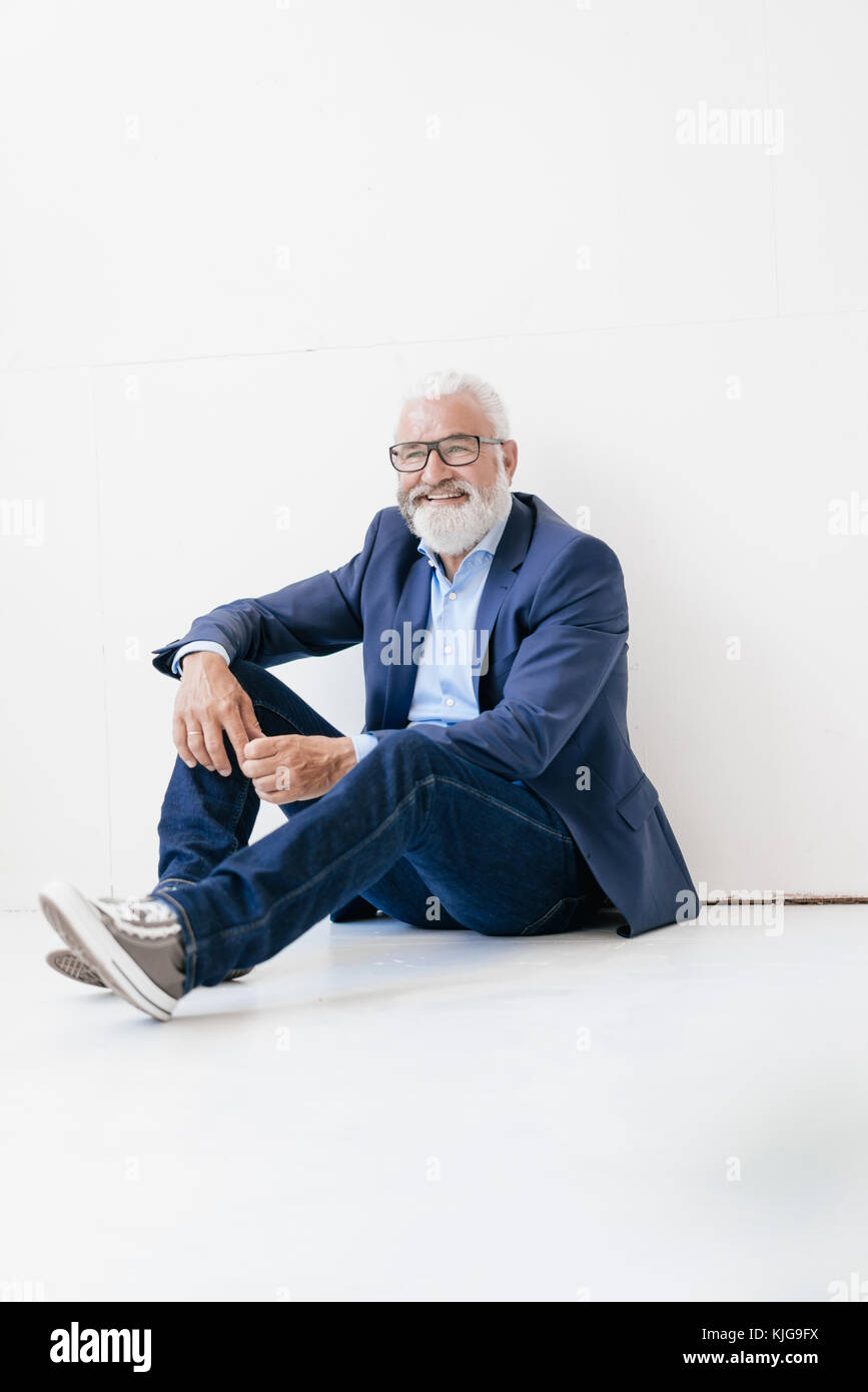 Smiling mature man sitting on the floor Stock Photo - Alamy