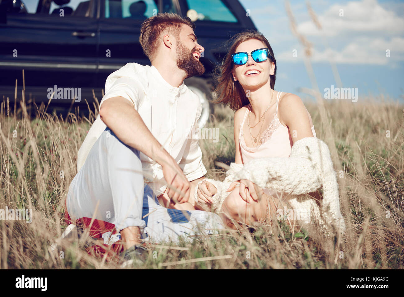 Cool couple laughing and sitting in grass, Krakow, Malopolskie, Poland Stock Photo