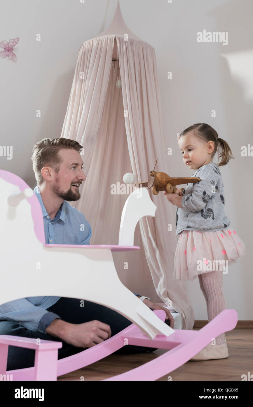 Father playing with toddler daughter in her nursery Stock Photo