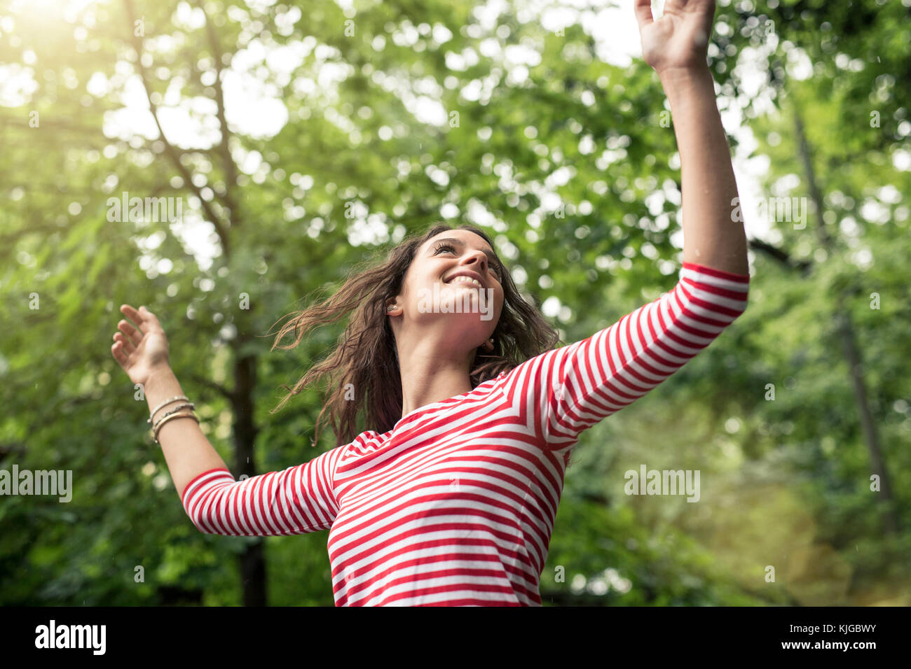 Happy young woman with raised arms dancing in nature Stock Photo - Alamy