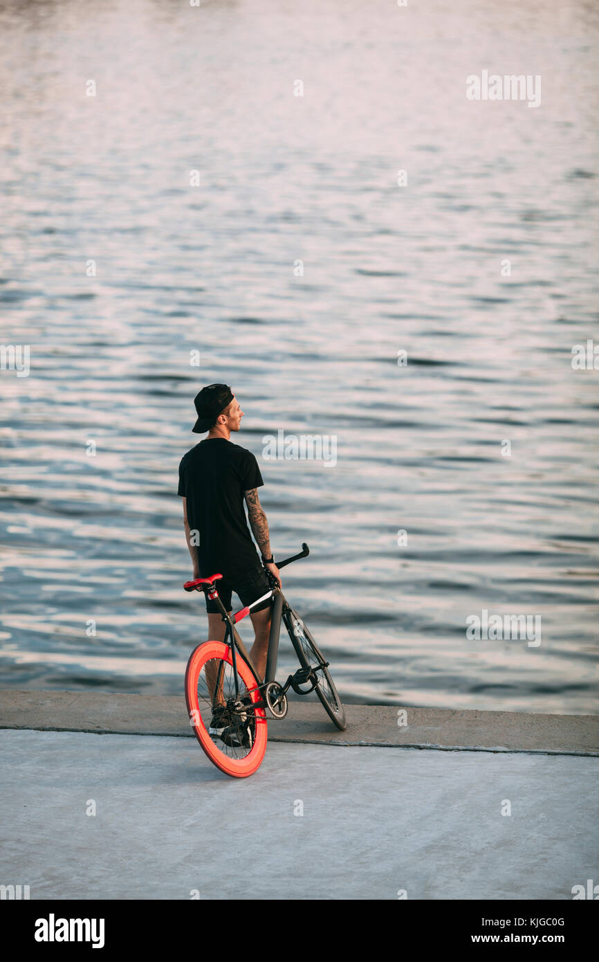 Young man with fixie bike at the waterfront Stock Photo
