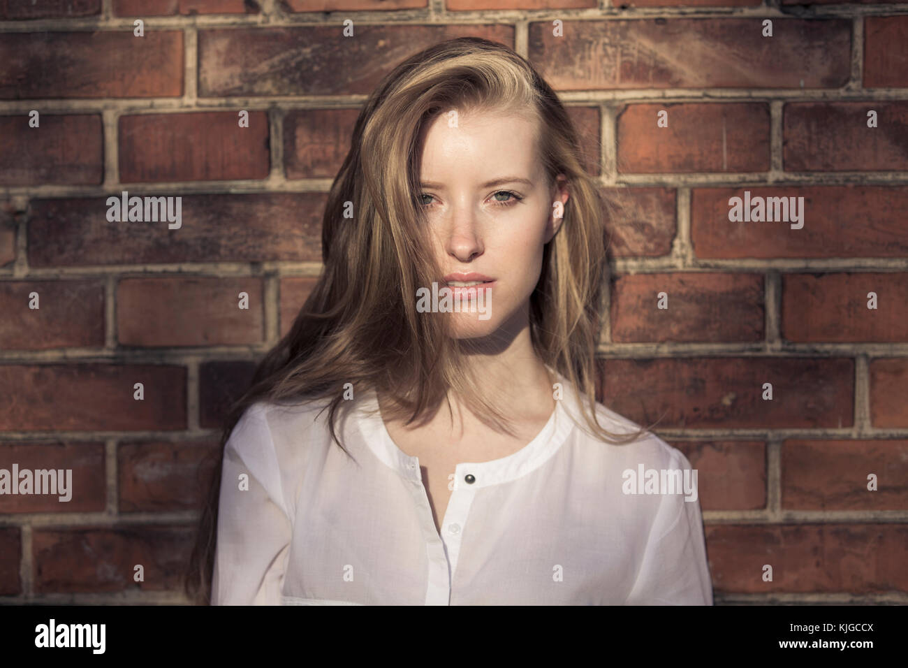 Portrait of young woman in front of brick wall Stock Photo - Alamy