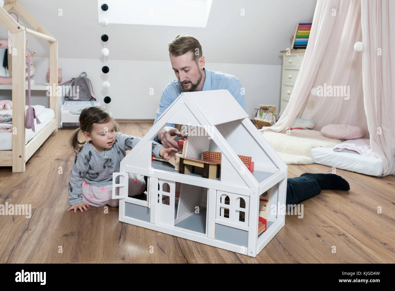 Father and toddler daughter playing with doll house in her nursery Stock Photo