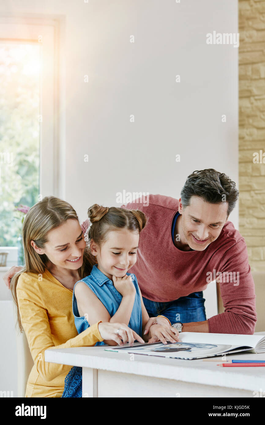 Happy family at home looking at picture book Stock Photo