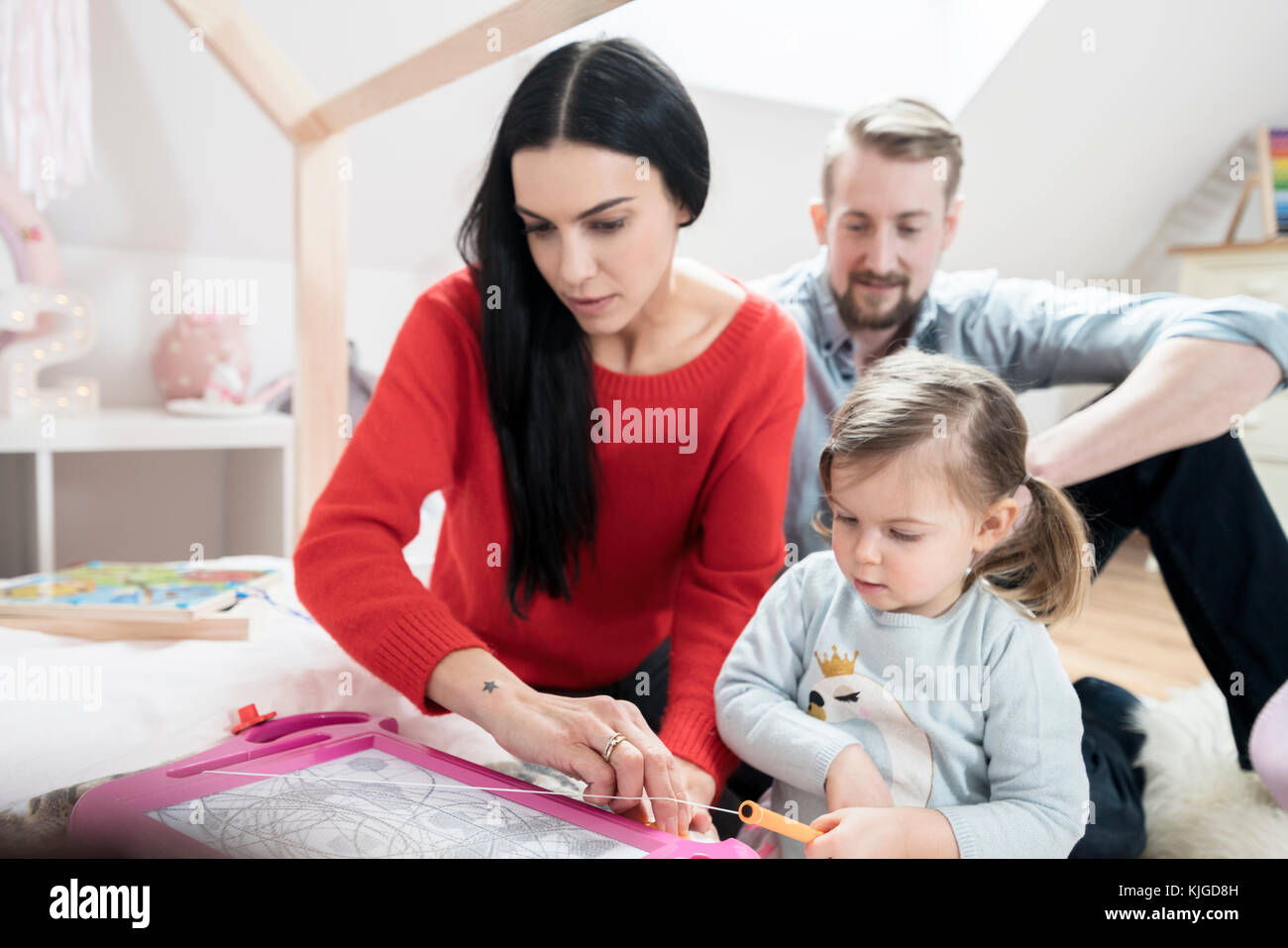 Parents playing with toddler daughter in nursery Stock Photo