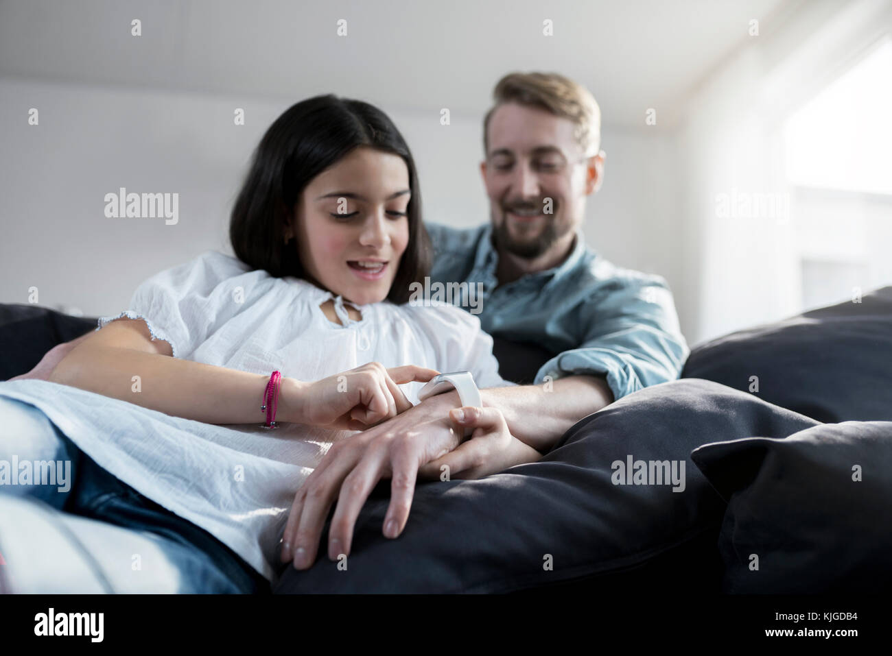 Daughter looking at her father's smartwatch Stock Photo