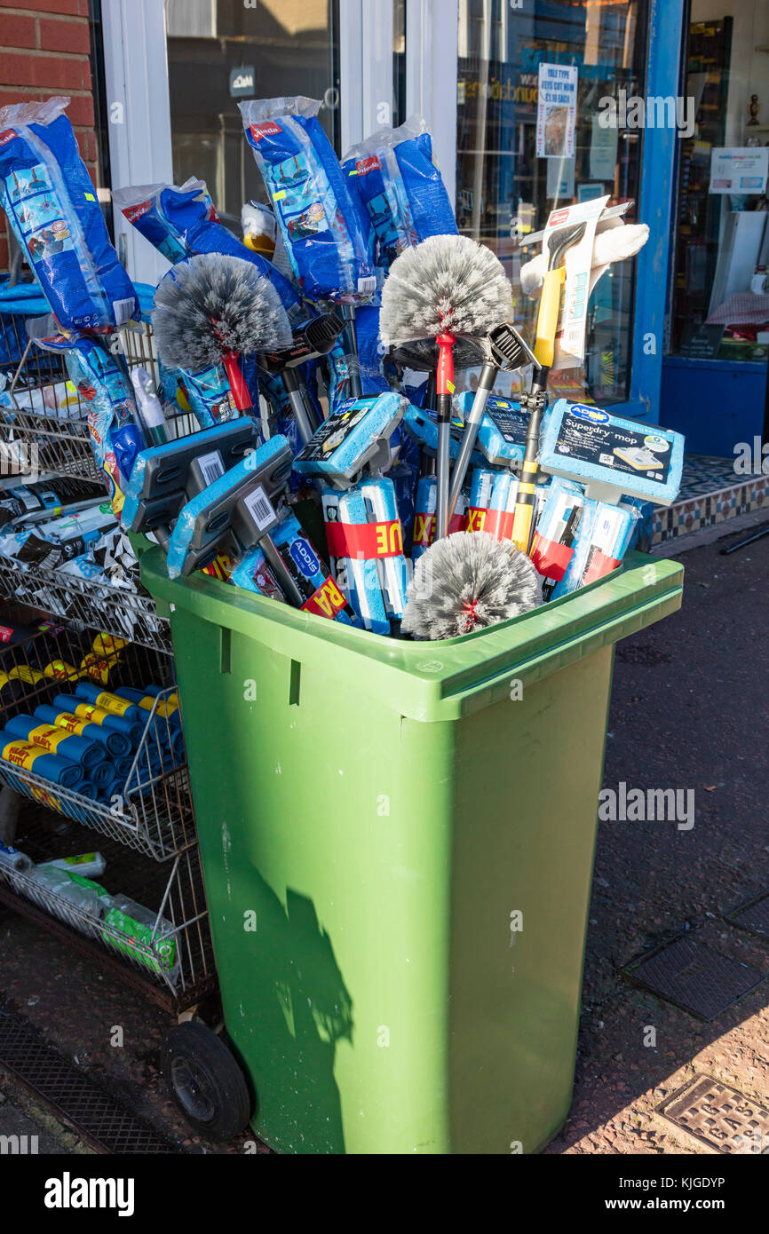 A collection of mops and brushes in a wheely bin outside an Ironmongers