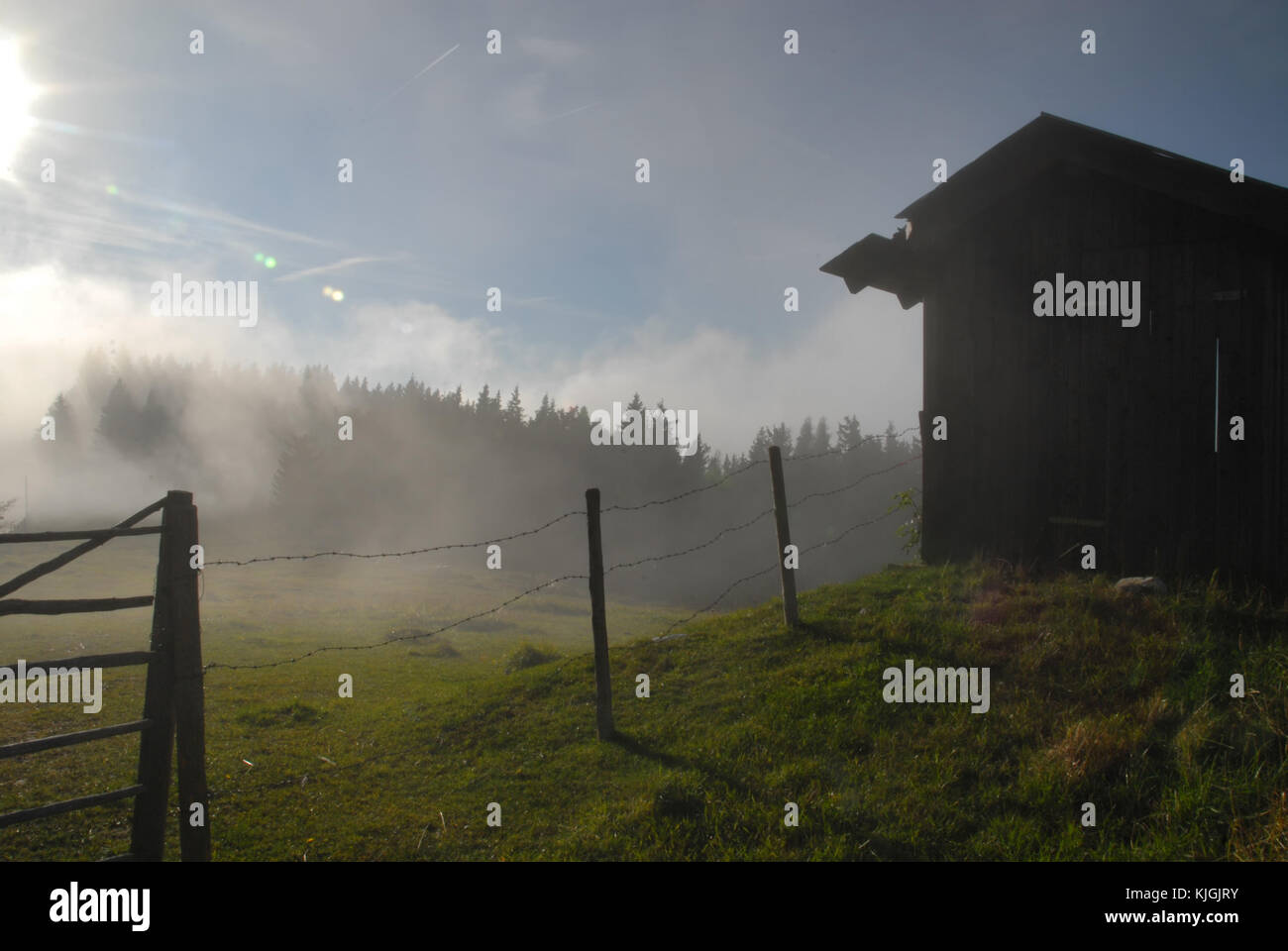 Fog in front of a barn and a fence on the mountain Schöckl near Graz, Austria Stock Photo