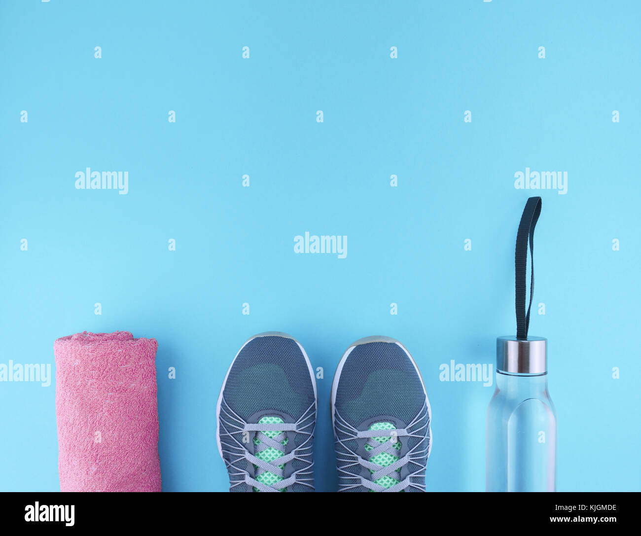 Flat lay shot of sneakers, water and pink towel on blue background with ...