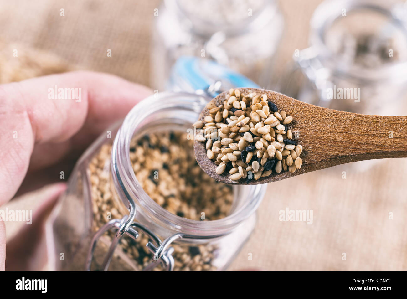 Sesame seeds in wooden spoon on top of a jar Stock Photo