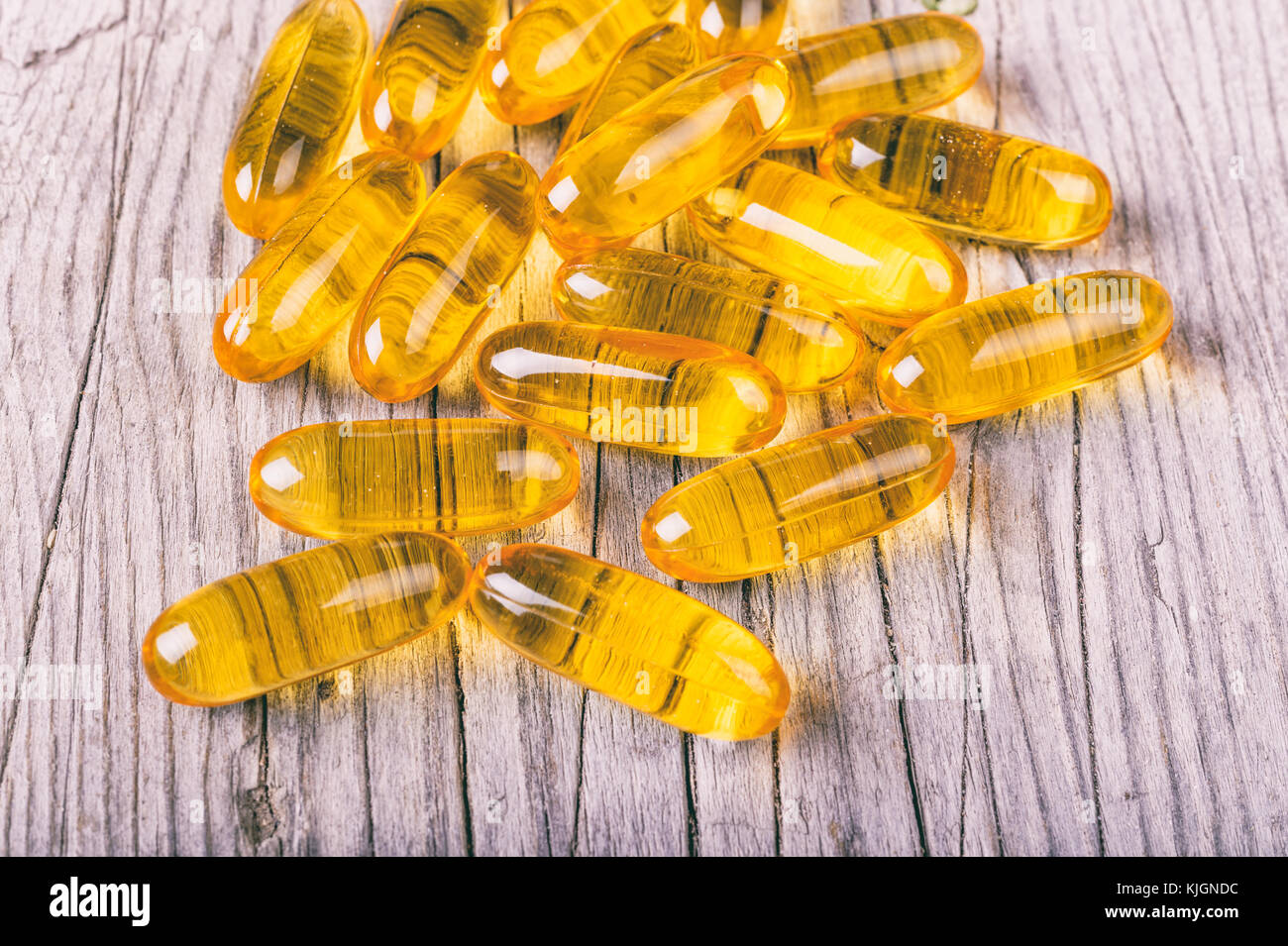 Close up of omega-3 fish fat oil capsules on wooden board Stock Photo