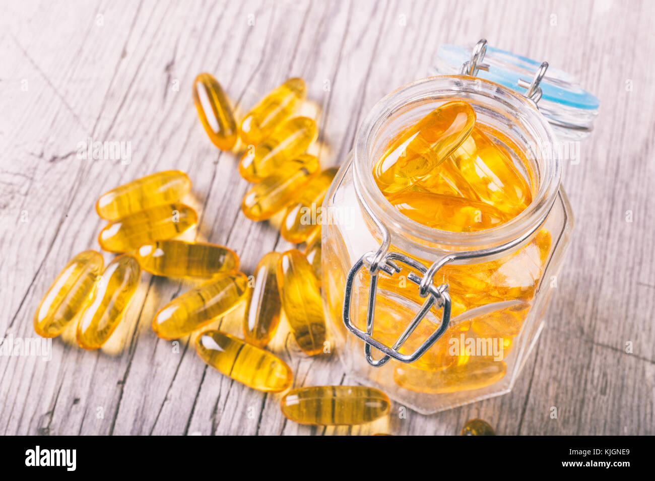 Close up of omega-3 fish fat oil capsules on wooden board in a jar Stock Photo